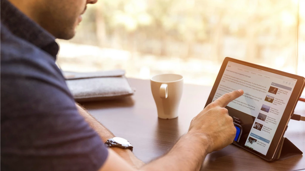 Man Using Ipad Sitting in Front of Desk