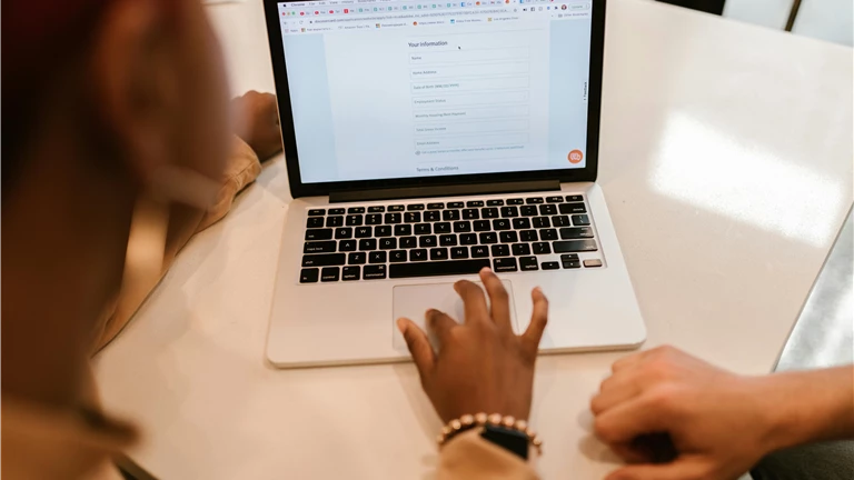 Close-Up Shot of a Person Filling out a Form Using a Laptop